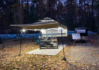 The VonBuckinator™ cleaning and lubricating a bike chain under an illuminated canopy at night